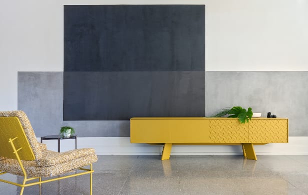 long yellow table and matching chair in front of patterned wall