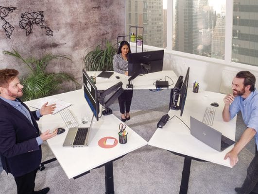 office with three people working at standing desks