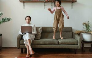 woman sitting on sofa working child jumping