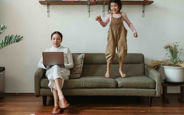 woman sitting on sofa working child jumping